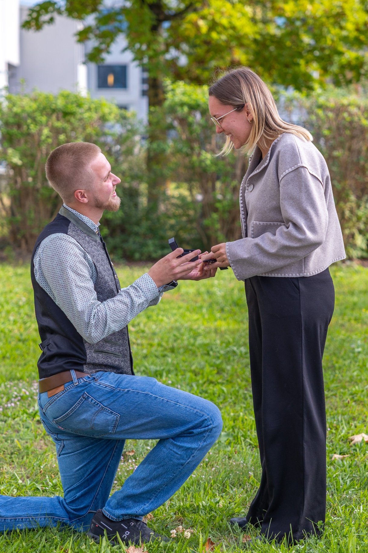 Heiratsantrag im Garten mit einem knienden Mann und seiner Partnerin
