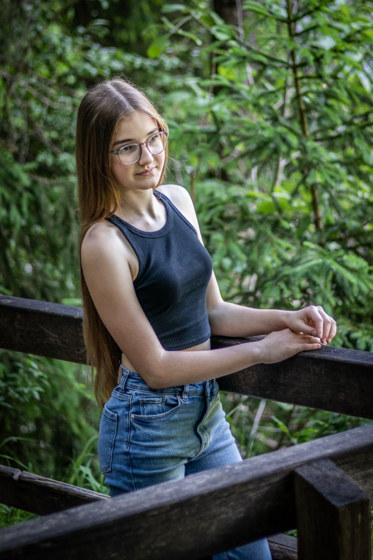Portrait einer jungen Frau an einem Holzgeländer im Grünen