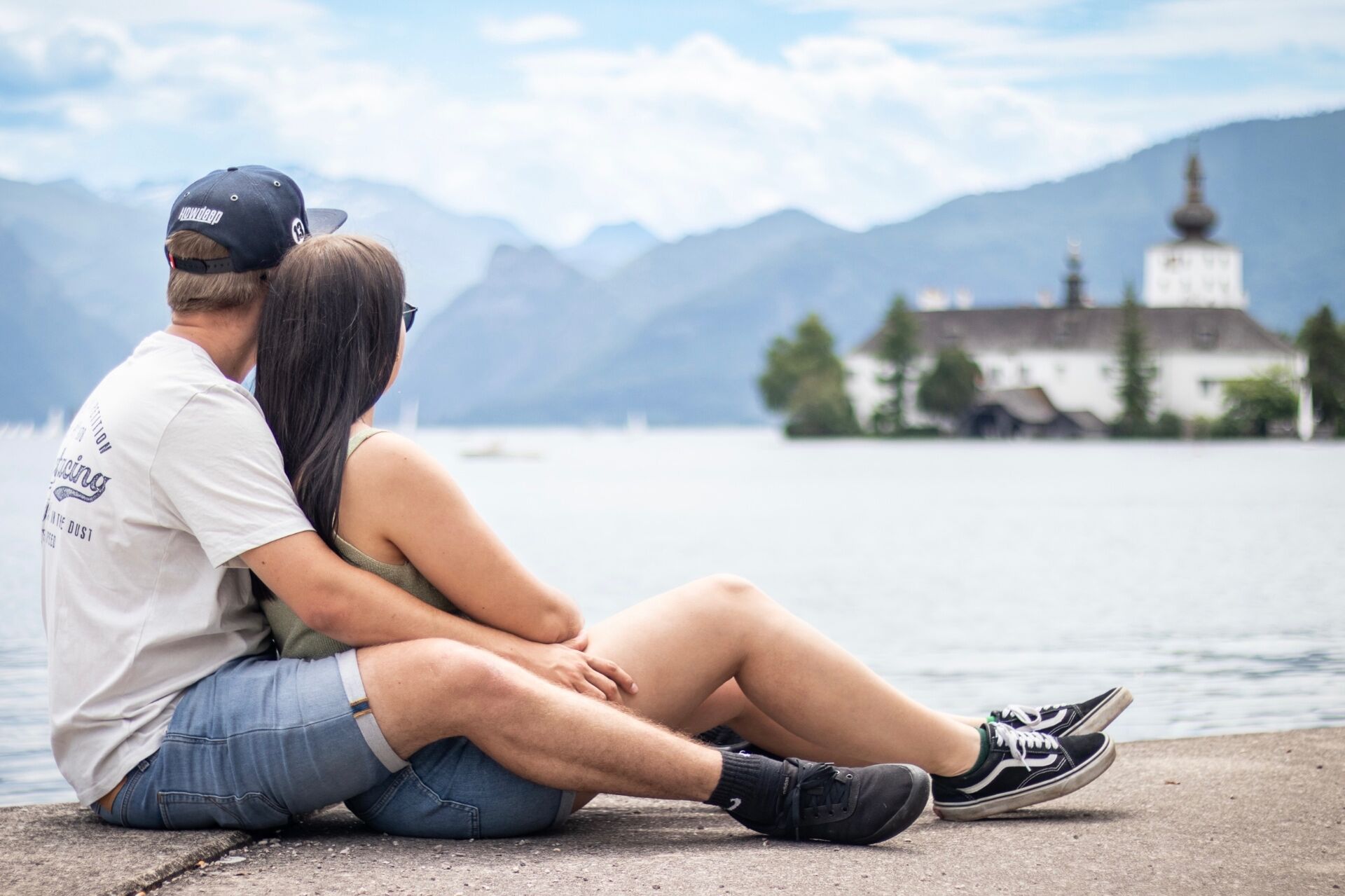 Paar sitzt am Seeufer vor Schloss Ort am Traunsee